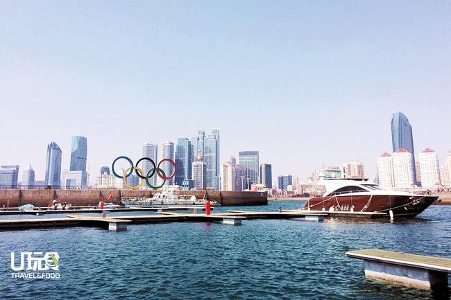 奥帆中心矗立着巨大的北京奥运火炬与奥运五环，港湾中停满帆船。