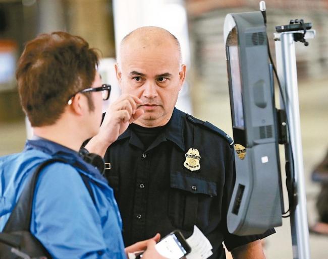 休士顿布希国际机场的海关与边境保护局人员协助旅客操作脸部扫描装置。