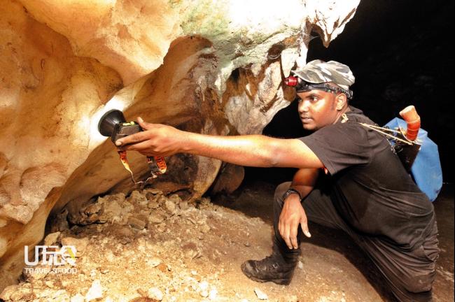 彼尔维用手电筒照射岩壁，讲解洞内从石灰岩变质，结晶形成的大理石区域。