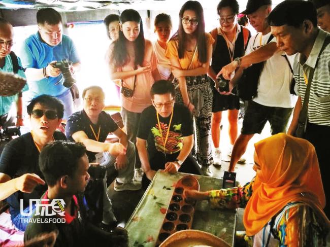 来自中国的游客对马来传统播棋（Congkak）非常感兴趣，围着向示范者了解玩法。