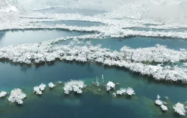 上面是雪白的冰瀑，下面是湛蓝的海子，四周是被大雪银妆素裹的丛林，一切都是静止地，美得那么不真实，让人以为走进了画里。