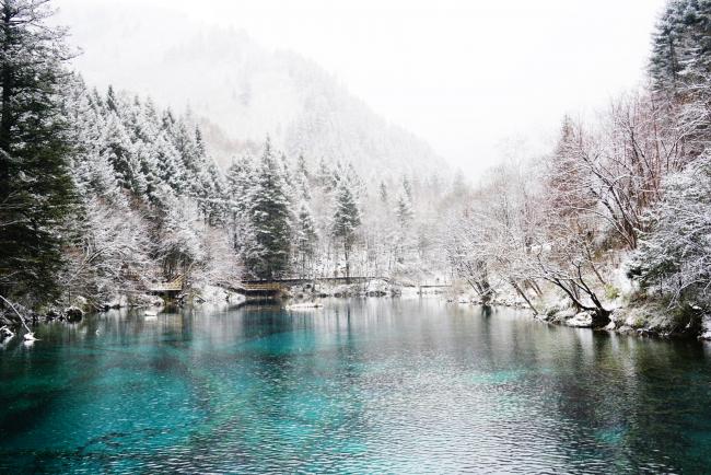 冬雪为九寨沟换上了素雅清逸的冬装，蓝色湖面的冰层在日出与日落间变换着奇妙的冰纹，冰瀑间隐隐传来动人悦耳的水流声。只有置身其中才能感受到那震人心魄的美，仿佛是人间中的「童话世界」。