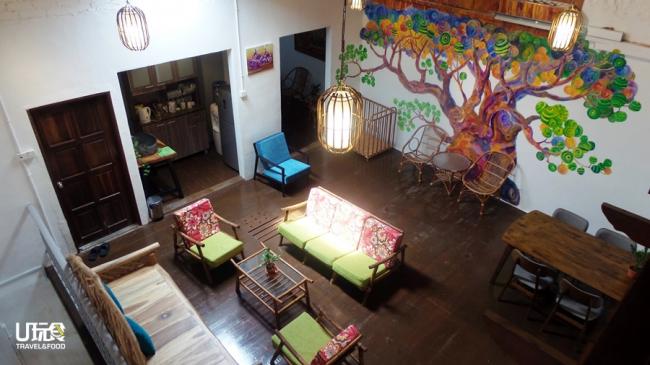 休息区墙上一大幅由怡保艺术家绘制的树林壁画，与老房子原木地板和客厅内的木制，竹藤家具摆饰品相映。