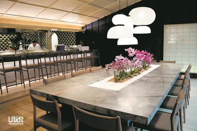 在寿司吧台前的大理石长桌上，以清雅的兰花点缀，营造出高雅脱俗的用餐氛围。