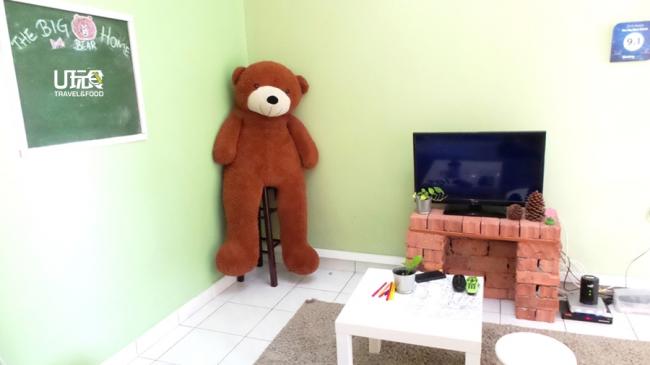 民宿主人「大熊」坐在客厅的高椅子上「欢迎」你一家的到来。