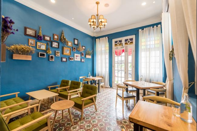 充满法式气质的蓝色墙壁之中附挂着款式各异的金色相框，突显咖啡馆独特的法式情怀。