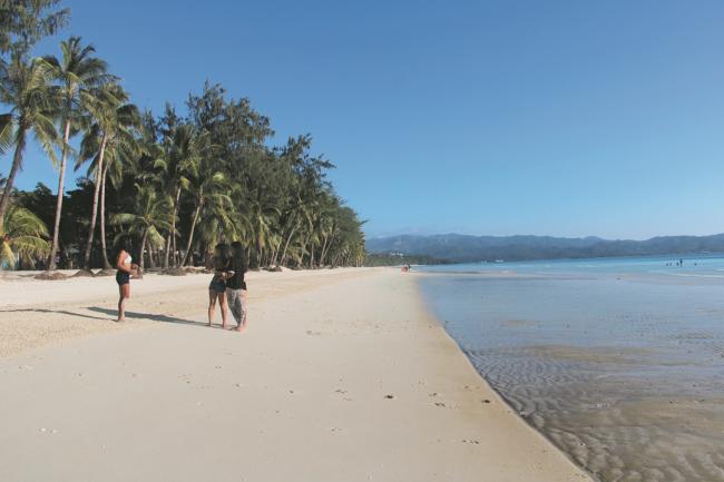 当地居民在洁白幼细的沙滩上漫步，偶尔停下以椰林作背景拍照。由于当局控制入岛人数，沙滩上变得幽静。 -法新社-