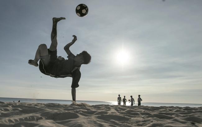 长滩岛的沙滩恢复干净，一群小孩在沙滩上踢足球，甚至单手倒立秀球技。 -法新社-