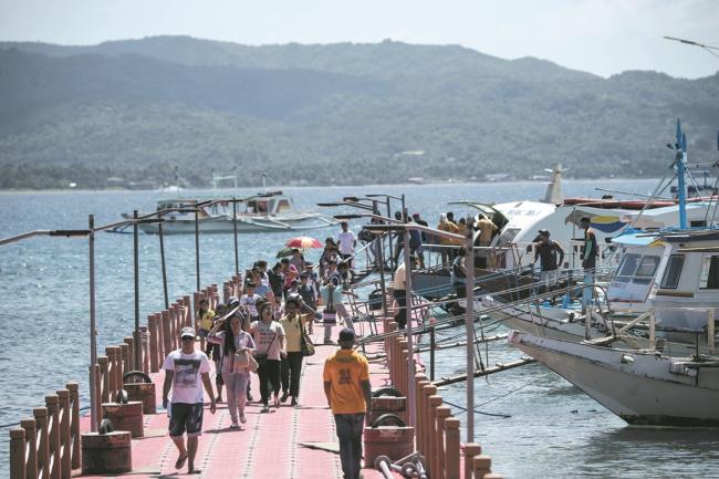 菲律宾政府为修复长滩岛，封岛6个月后在周五正式重开。当局本月15日起，已先对菲律宾游客开放10天测试营运，周四可见有居民和游客，在长滩岛上的码头搭船离开，或刚抵达下船。 -法新社-