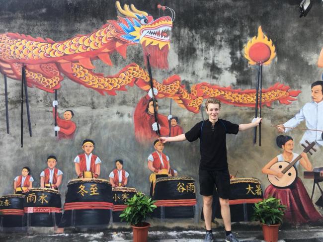 外国游客到麻坡游玩，对于舞龙主题璧画深感好奇。
