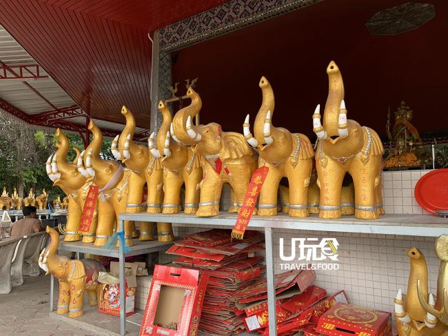 四面佛寺周围的金象被祭拜者们挂上了花圈以及红布条，有着心想就会事成的寓意。
