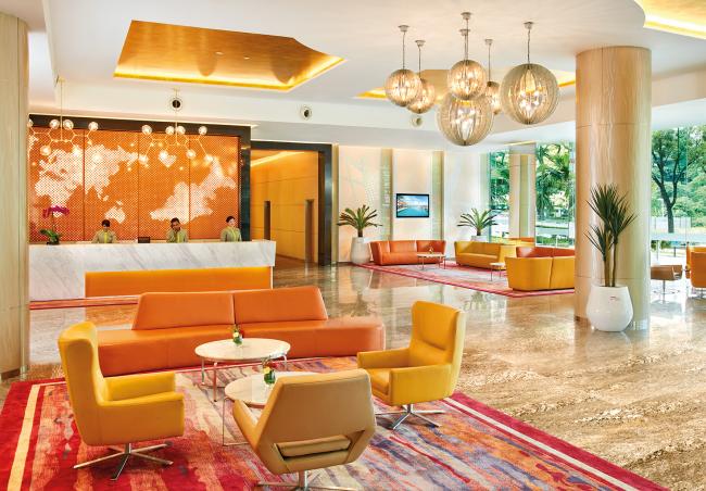 酒店大厅以白、橘和金色调相互配合，明亮宽敞的大厅显得十分大气。为遵守新常态的操作程序，等候区已贴上了安全贴纸，柜台也已安上了透明隔离板，致力于为住客们的安全与卫生提供保障。