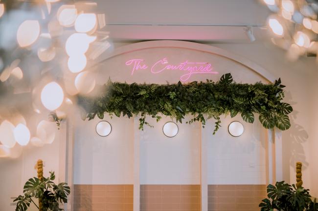 粉白色调与霓虹灯装置、绿植相互衬托的瓷砖墙，灵感源于法式庭院的设计。这个角落成了让访客们留步的打卡热点。