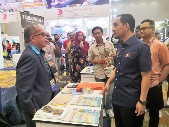 翁哈菲兹（右）参观2023年柔州马来西亚国际旅游展摊位时，不忘询问旅游配套详情。